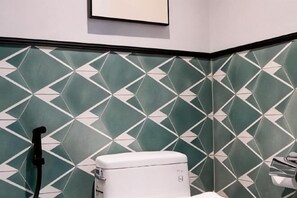 Un baño con un estampado geométrico de azulejos, un inodoro y un secador de manos.