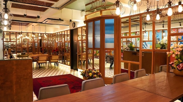 Un restaurant avec des meubles en bois, une moquette rouge et une cloison décorative en verre.