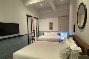 Une chambre d’hôtel avec deux lits, une télévision, un grand miroir et une vue sur un balcon.