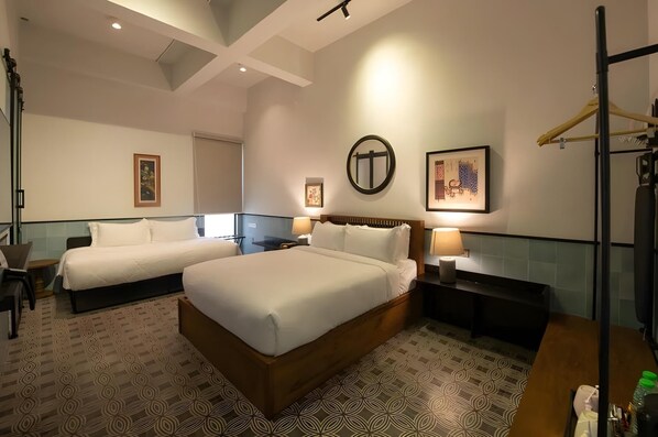 Une chambre d’hôtel avec deux lits, un miroir, des œuvres d’art accrochées aux murs et une tête de lit en bois.