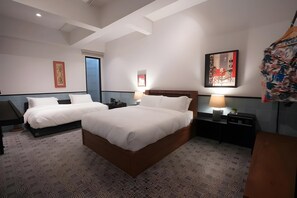Une chambre d’hôtel avec deux lits, une table de chevet avec une lampe, une œuvre d’art accrochée au mur et une porte dotée d’un cadre bleu.