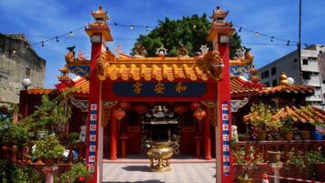 A traditional Chinese temple with ornate architecture, a central altar, and surrounding potted plants.