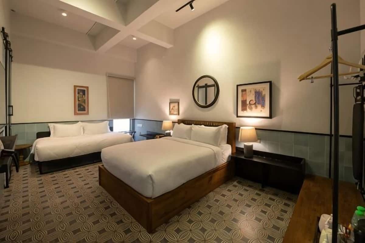 A hotel room with two beds, a desk, a chair, a mirror, and a TV.