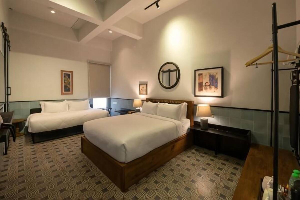 Een hotelkamer met twee bedden, een bureau, een stoel, een spiegel en een televisie.