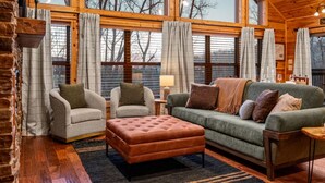 A cozy room with a green sofa, two armchairs, a wooden coffee table, and a fireplace. - Freshly Renovated! Pickleball, Hot Tub, Game Rm! (Gatlinburg)
