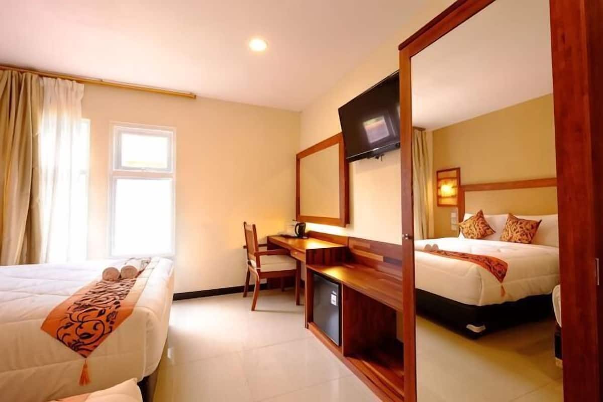 Une chambre d’hôtel avec deux lits, un bureau, une télévision et un miroir.