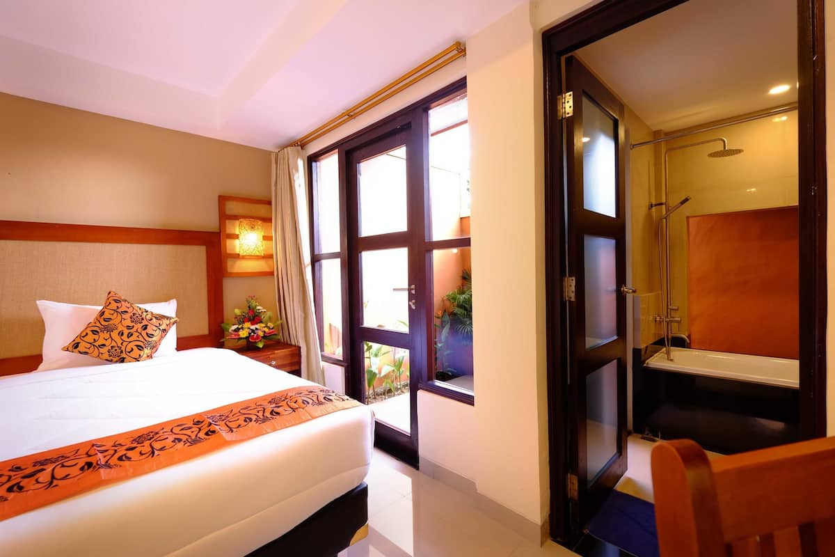 Une chambre d’hôtel avec un lit, une douche et une vue sur l’extérieur, visible à travers une porte vitrée.