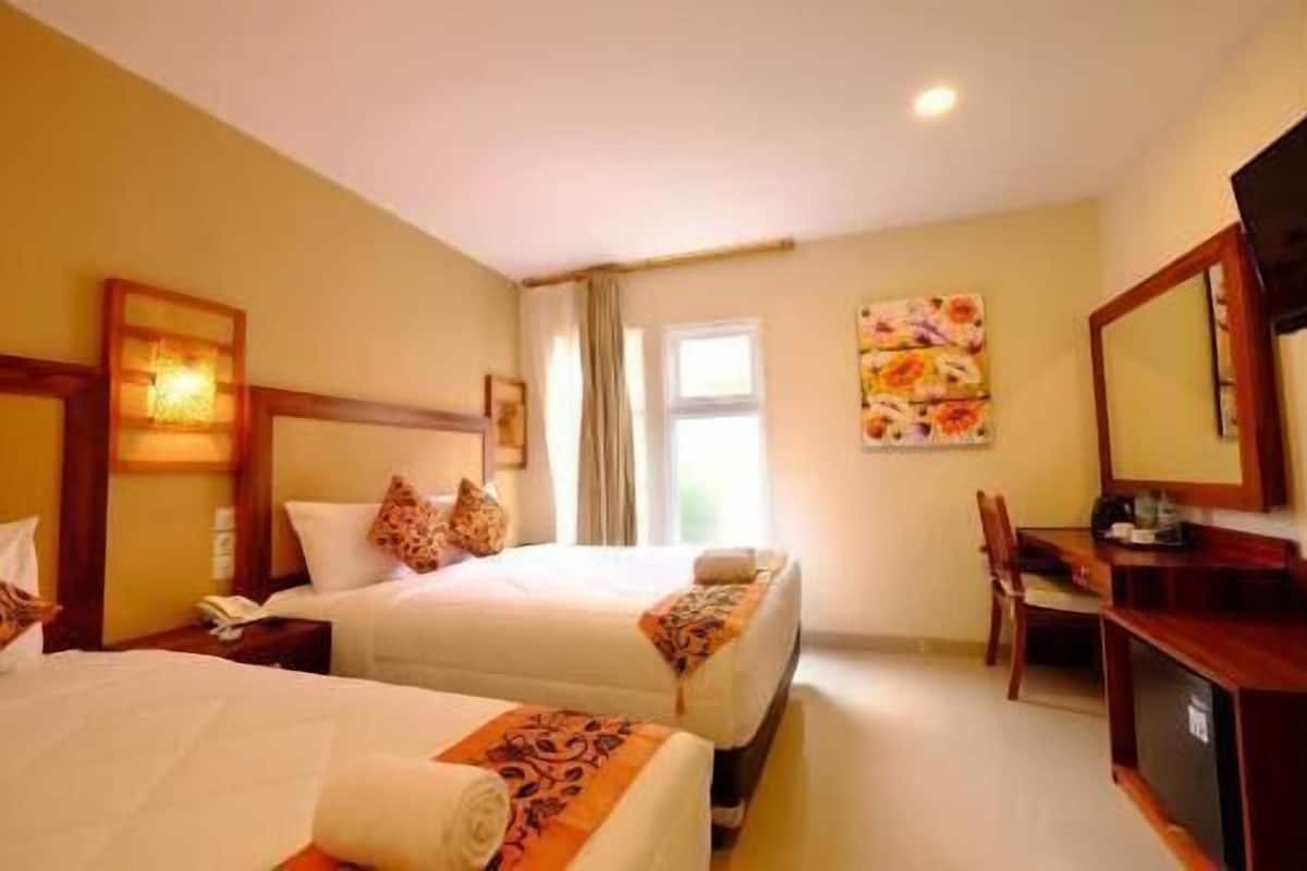 Une chambre d’hôtel avec deux lits, un bureau, une chaise, une télévision et une fenêtre.
