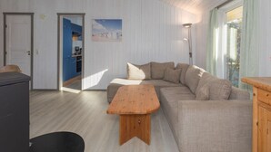 A living room with a sectional sofa, a wooden coffee table, and a kitchen visible through an open door. - Ferienhaus mit Sauna im Ferienpark Mirow (Mirow)