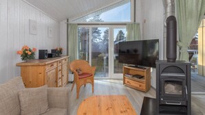 A cozy living room with a wooden sofa, a TV, a fireplace, and a dining table. - Ferienhaus mit Sauna im Ferienpark Mirow (Mirow)