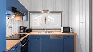 A modern kitchen with blue cabinets, a wooden countertop, a built-in oven, a microwave, and a window above the sink. - Ferienhaus mit Sauna im Ferienpark Mirow (Mirow)