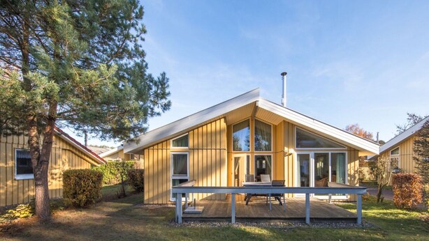 A modern, single-story house with large windows and a wooden exterior. - Ferienhaus mit Sauna im Ferienpark Mirow (Mirow)