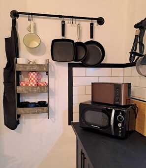 Kitchen area with microwave, pot, and pan storage.