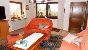 Una sala de estar con sofá, sillón y una mesa con un plato decorativo.
