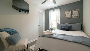 A bedroom with a bed, a chair, a ceiling fan, and artwork on the wall. - 3-bedroom 2 full bath bungalow in the heart of the city minutes from DT Raleigh. (Raleigh)