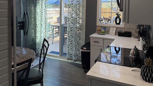 A modern kitchen with a dining area, a refrigerator, a coffee machine, and a window with a 'welcome' sign. - 3-bedroom 2 full bath bungalow in the heart of the city minutes from DT Raleigh. (Raleigh)