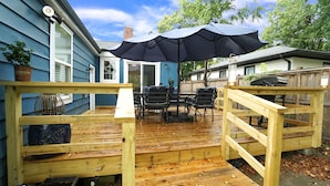 A wooden deck with a table and chairs, an umbrella, and a brick chimney. - 3-bedroom 2 full bath bungalow in the heart of the city minutes from DT Raleigh. (Raleigh)