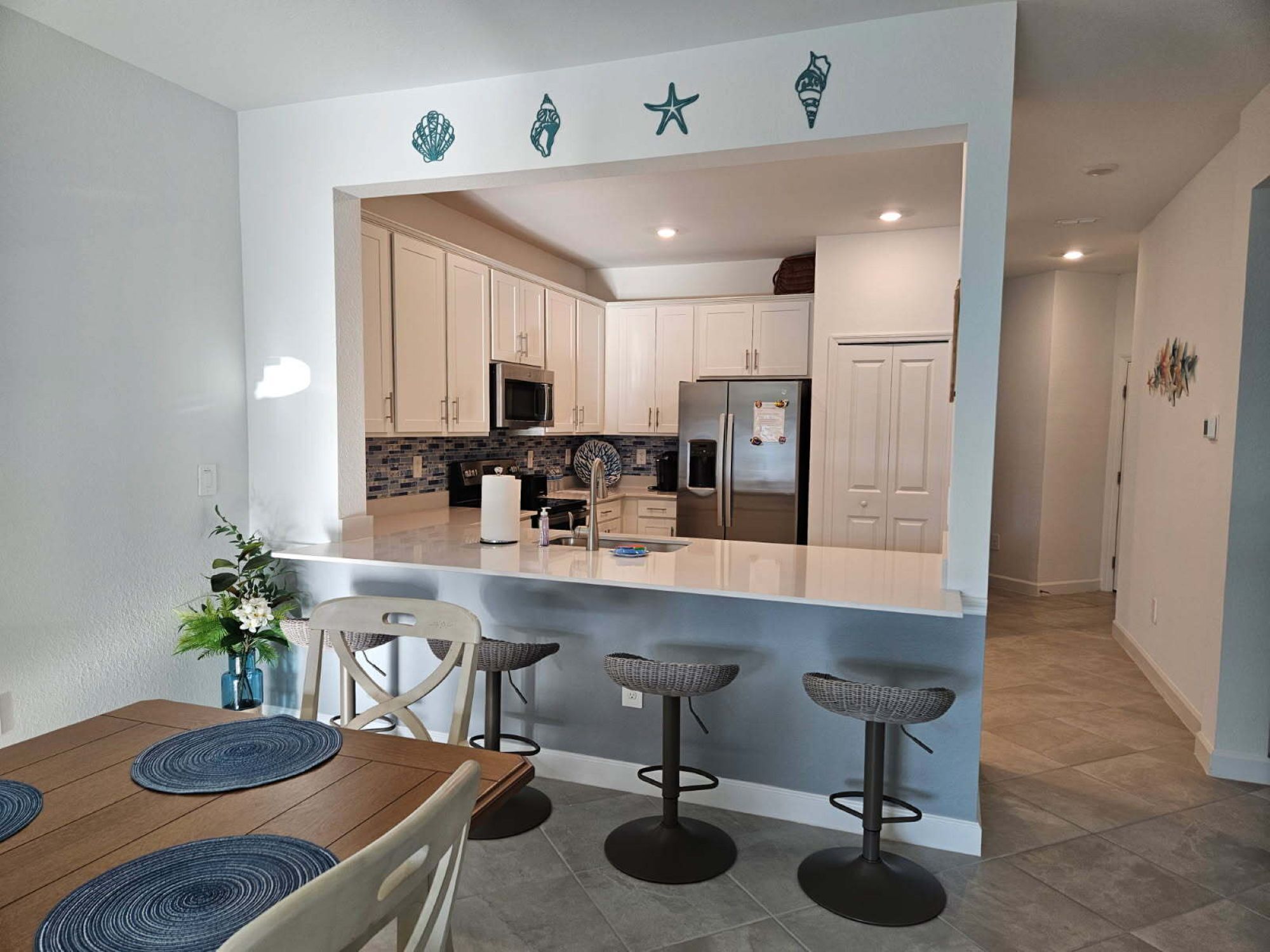 A modern kitchen with a central island, bar stools, and a dining table.
