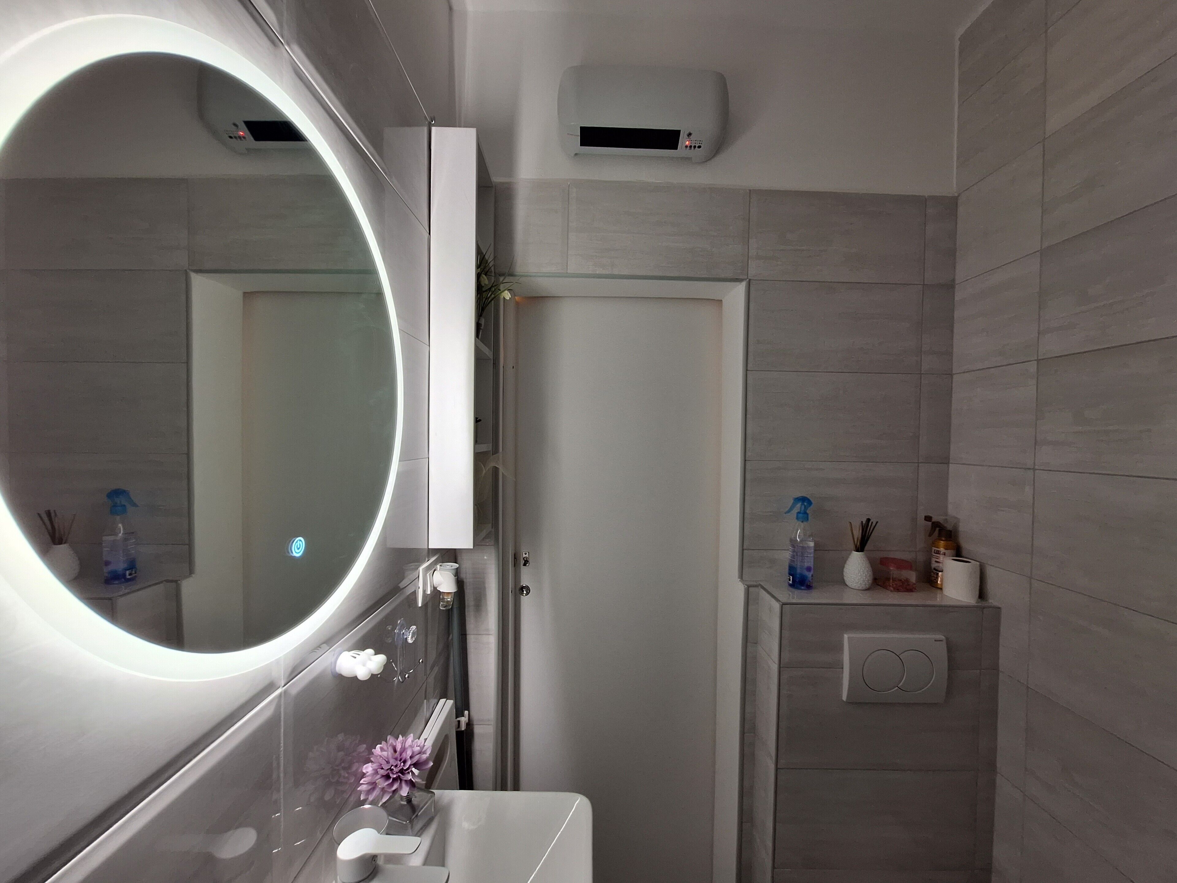 Een moderne badkamer met een grote spiegel, een handdouche en een toilet.