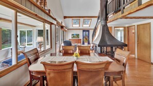 A dining area with a large table, wooden chairs, and a chimney. - Private Dock & Lake Views: Home on Lime Lake (Machias)