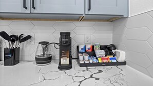 Une cuisine équipée d’une machine à café, de capsules de café et d’ustensiles de cuisine.