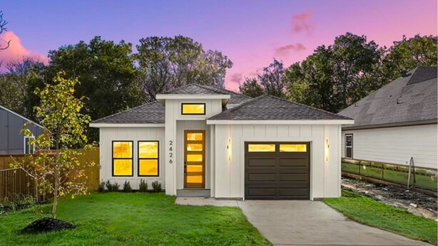 Une maison à deux étages avec un garage, une pelouse bien entretenue et une allée.