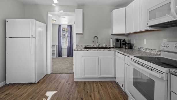 A modern kitchen with white cabinets, a built-in oven, and a microwave.