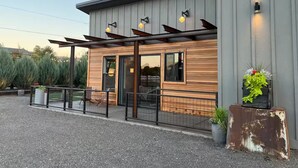 Een modern gebouw met een houten gevel, grote ramen en een overdekt terras.