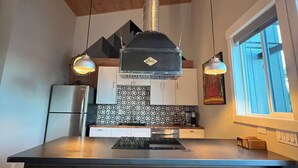 Een moderne keuken met een centraal eiland, hanglampen en een inbouwfornuis.