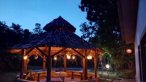 A gazebo with a tiled roof, a central table, and hanging lights. - Casa Naranjo (Caicedonia)