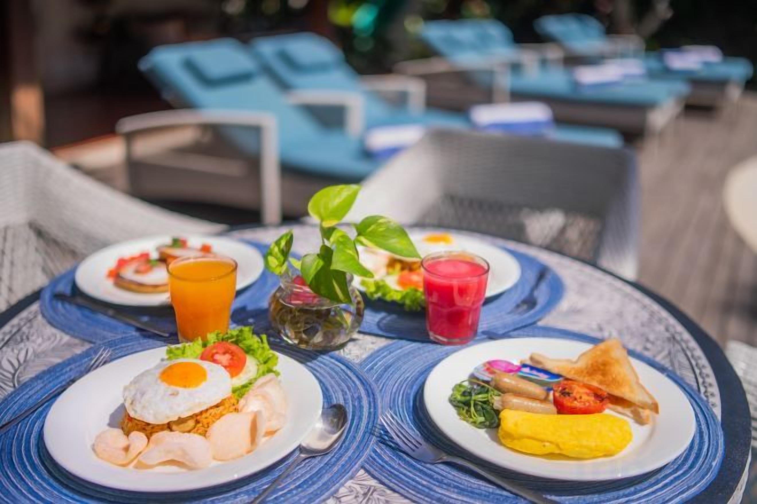 A table with plates of food and drinks, surrounded by lounge chairs.