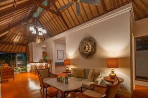 A cozy living area with a high ceiling, a round wall decoration, and a dining table with chairs.