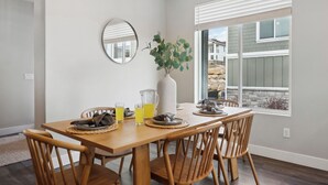 A dining area with a wooden table, four chairs, a vase with greenery, a pitcher, and glasses of yellow drink. - 2 Suites|Hot tub|Arcade|BBQ|ESPN|H20+|No Cheap TP (Midway)