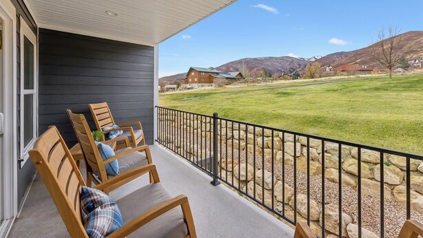 A covered porch with wooden chairs and a stone wall. - 2 Suites|Hot tub|Arcade|BBQ|ESPN|H20+|No Cheap TP (Midway)