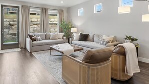 A modern living room with a sofa, two armchairs, a coffee table, and a dining table. There are potted plants and a small window with a view of the outdoors. - 2 Suites|Hot tub|Arcade|BBQ|ESPN|H20+|No Cheap TP (Midway)