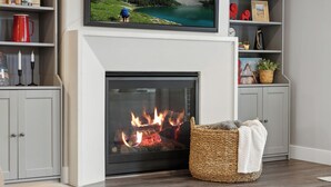 A fireplace with a TV above it, a basket with a blanket, and a bookshelf with various items. - 2 Suites|Hot tub|Arcade|BBQ|ESPN|H20+|No Cheap TP (Midway)