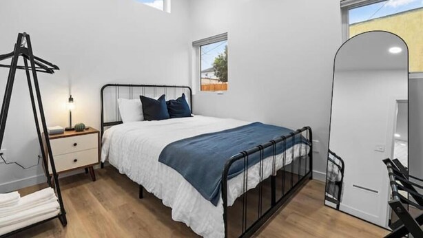 A bedroom with a bed, bedside table, lamp, and a window.