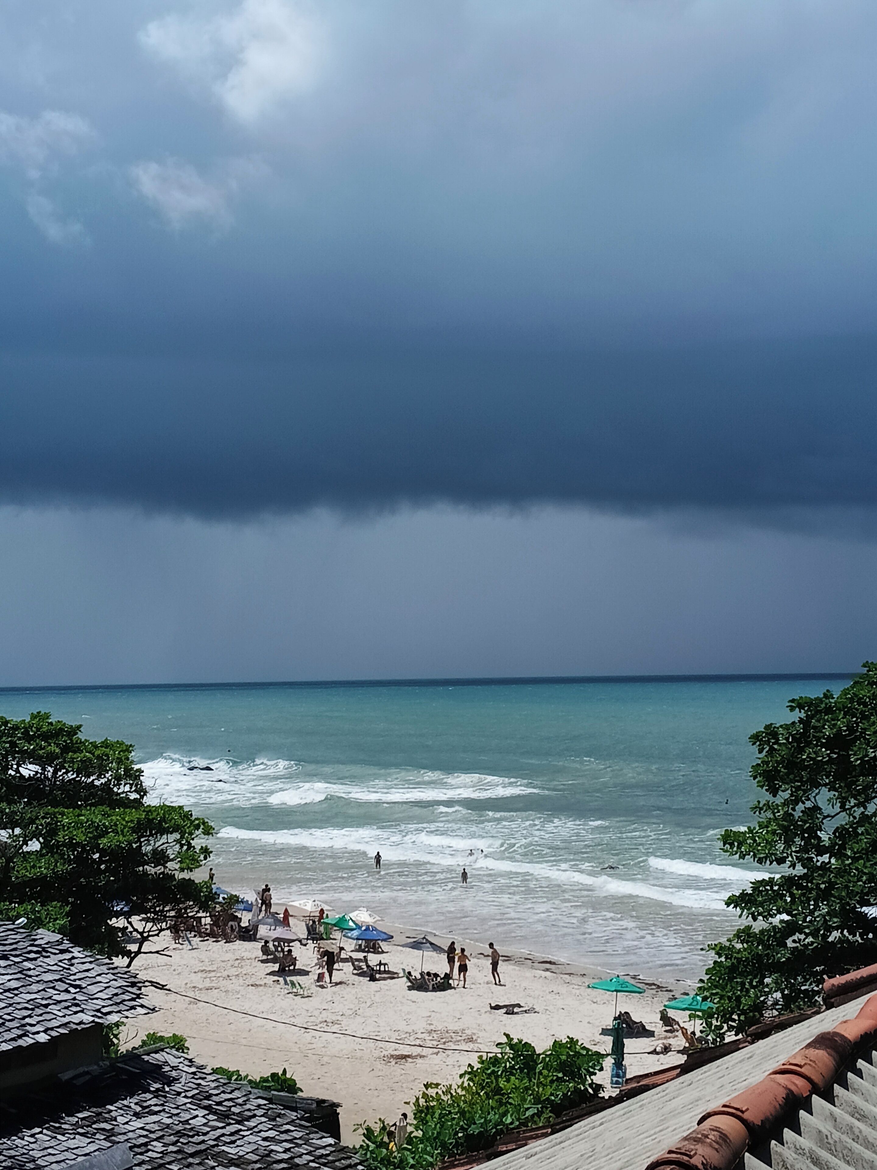 Na praia, areia branca, barracas de praia de cortesia, guarda-sóis 