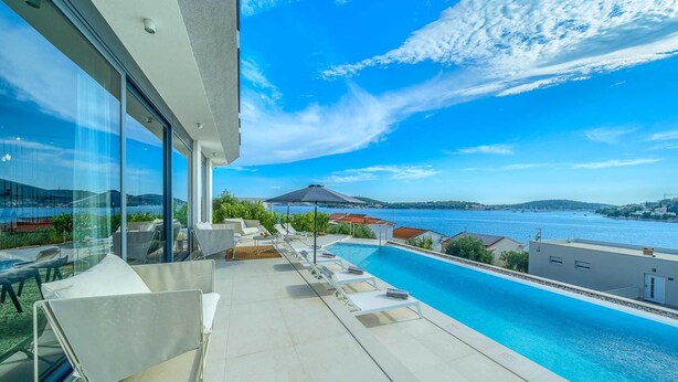 A modern outdoor pool area with lounge chairs and a view of the sea. - Luxurious 5-BR Villa for 10 with Panoramic Views and Heated Pool (Zatoglav)
