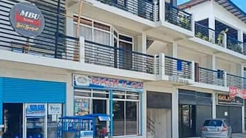 Um edifício de vários andares com estabelecimentos comerciais no térreo, incluindo uma vitrine visível com a placa 'WASTN GO'.