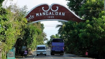 A road sign with the text 'ante MANGALDAN 1600' and a bus passing by.