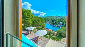 A balcony with a view of a coastal town, a swimming pool, and lounge chairs. - Spacious 4-Bedroom Villa for 8, with heated pool and sea views (Bobovisca)