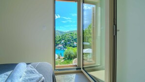 A bedroom with a large sliding glass door leading to a balcony with a scenic view of a lake and houses. - Spacious 4-Bedroom Villa for 8, with heated pool and sea views (Bobovisca)