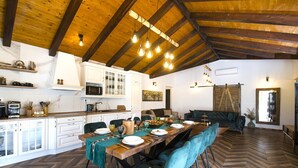Una cocina amplia con armarios blancos, una mesa de madera para seis personas y un suelo con patrón de espiga.
