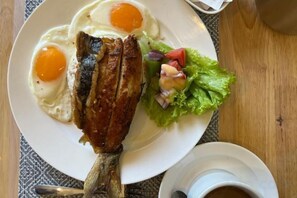 A plate with fried fish, eggs, and a salad on a table. - OSEIDON HOTEL BORACAY (Boracay Island)