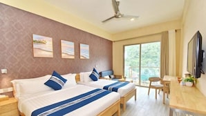 A hotel room with two beds, a desk, a chair, a TV, and a window with a view of greenery.