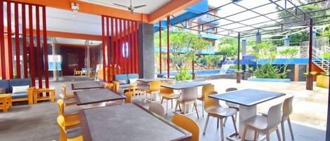 An outdoor seating area with tables and chairs, a covered section, and a view of the outdoors.
