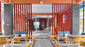 A modern indoor seating area with tables and chairs, wooden accents, and a view through a glass partition.