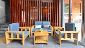 A modern lobby with a blue sofa set, wooden chairs, and a coffee table.