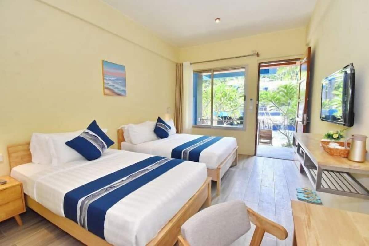 Hotellihuone, jossa on kaksi sänkyä, televisio, ruokapöytä ja näkymä ulos.